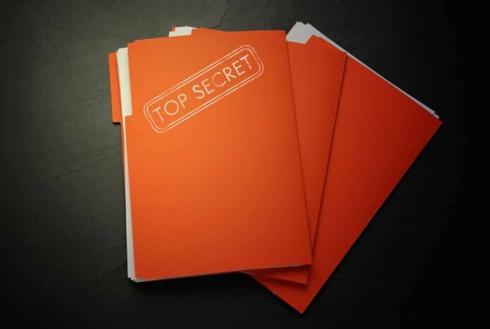 A stack of orange folders labeled 'TOP SECRET' on a dark surface