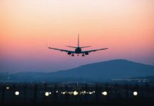An airplane approaching for landing against a colorful sunset sky
