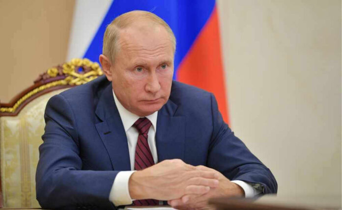 shutterstock_2329478503 Vladimir Putin in a suit sits at a table.