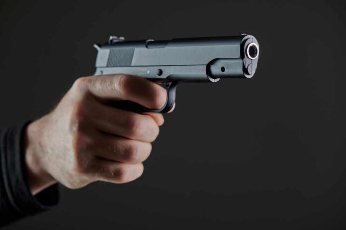 Hand holding a semi-automatic pistol pointed forward