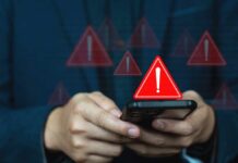 Americans Drown in AI Scams Hands holding a smartphone with red warning icons appearing on screen