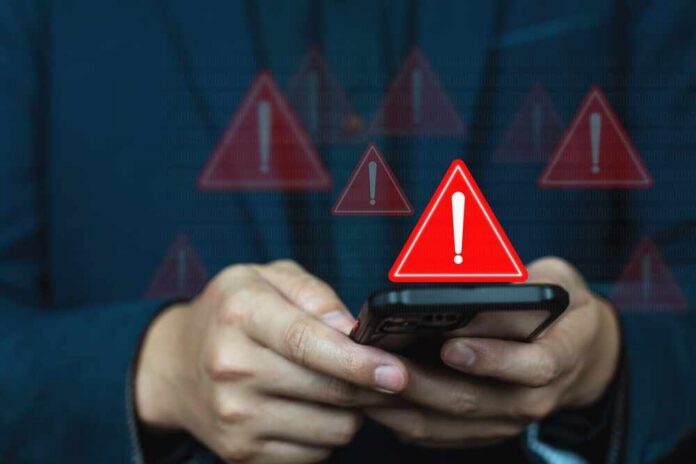 Application,Alert,Information,And,Alert,Warning,Popup,And,Error,System Hands holding a smartphone with red warning icons appearing on screen