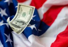A hundred dollar bill resting on an American flag
