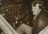 Amelia Earhart seated in an airplane cockpit, looking toward the camera