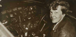 Amelia Earhart seated in an airplane cockpit, looking toward the camera