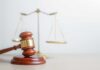 Judge Approves Democrat Raid A wooden gavel in front of a balance scale symbolizing justice