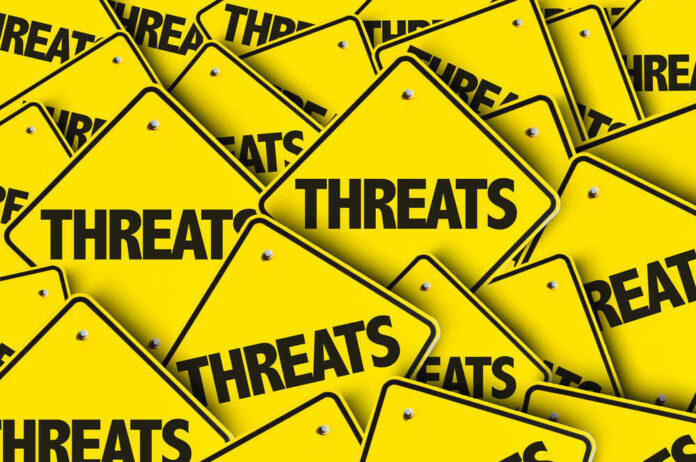 shutterstock_489638770 Yellow signs with the word threats overlapping